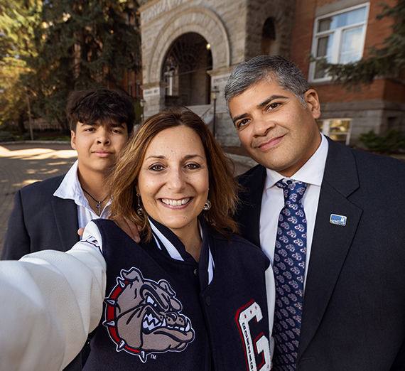GU bulldog head logo and Pac-12 logo side-by-side over a photo of the Gonzaga University campus at sunset.